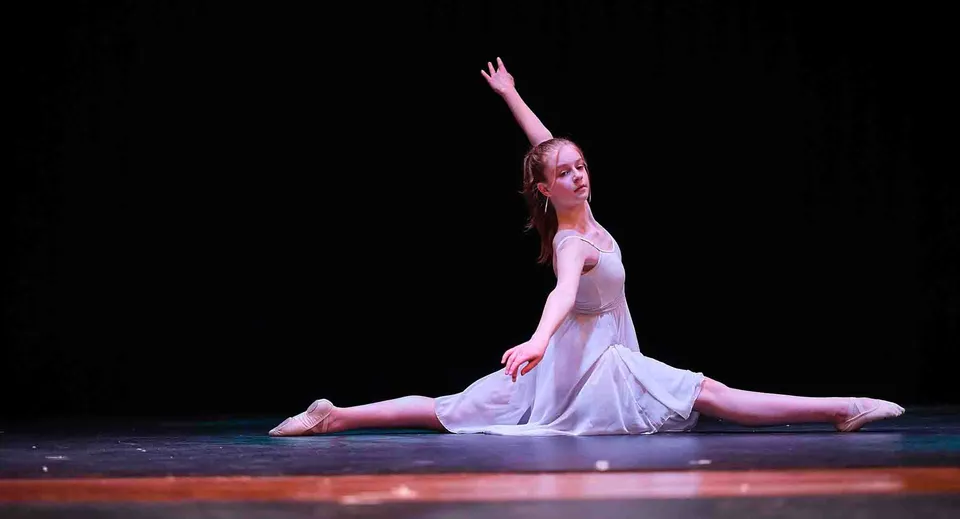 Una ballerina in abito bianco si esibisce sul palco della St. Mary's School.