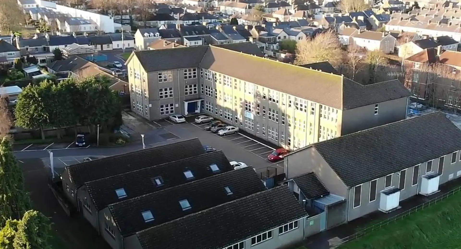 L'edificio principale a più piani del Coláiste Éamann Rís si trova in primo piano con la città sullo sfondo.