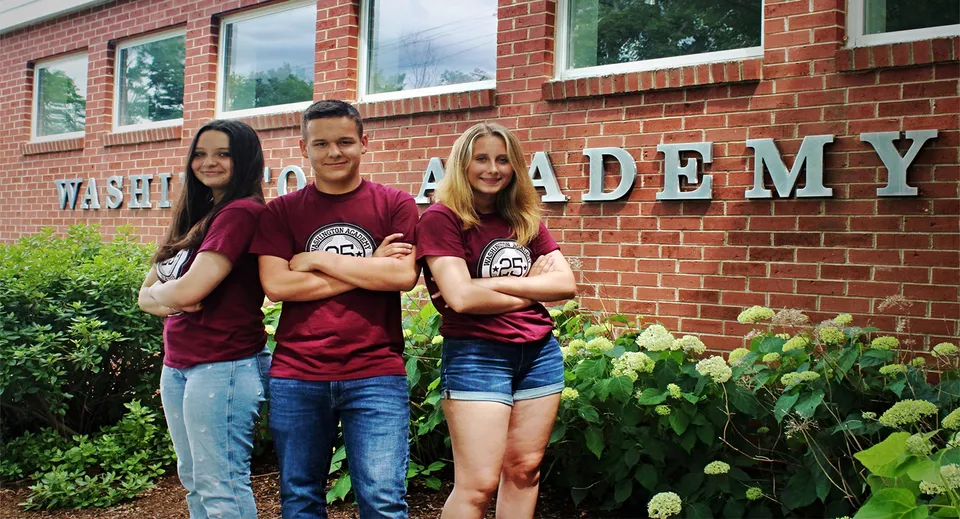 Tre studenti posano per una foto davanti a un edificio in mattoni della Washington Academy.