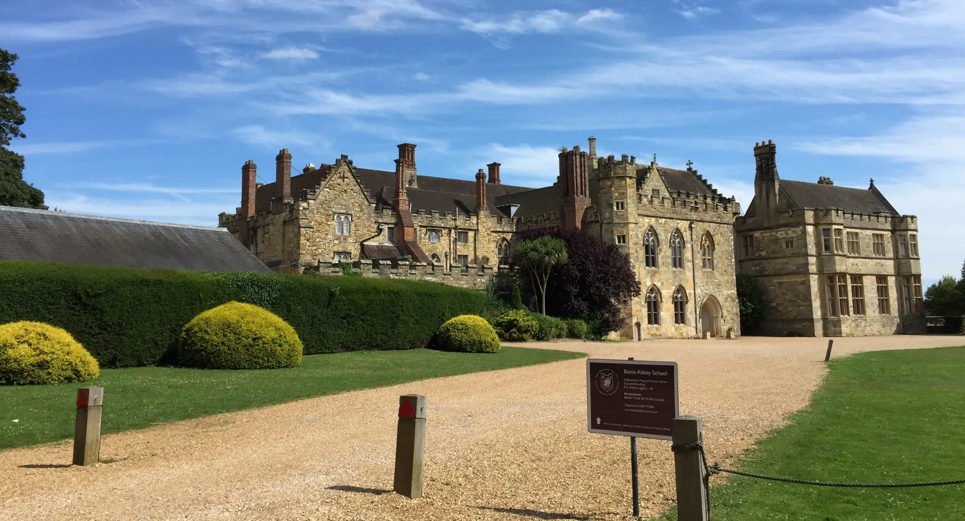 Il castello medievale nei terreni della Battle Abbey School con un prato ben curato e un vialetto di ghiaia in primo piano.