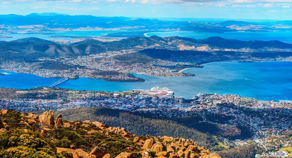 Vista aerea di una città costiera con montagne e acqua nei pressi della Hobart City High School.