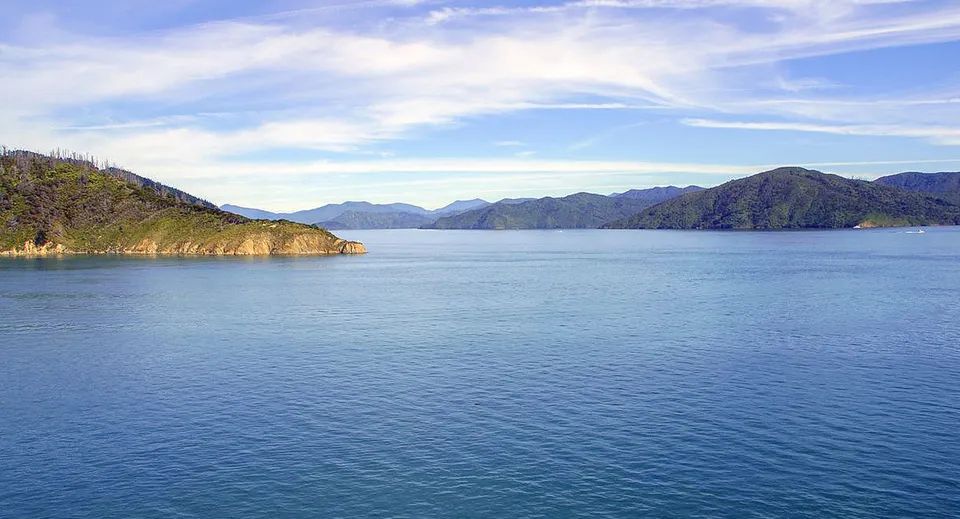 Un lago tranquillo con montagne e cielo blu nell'ambiente naturale della Queens High School.