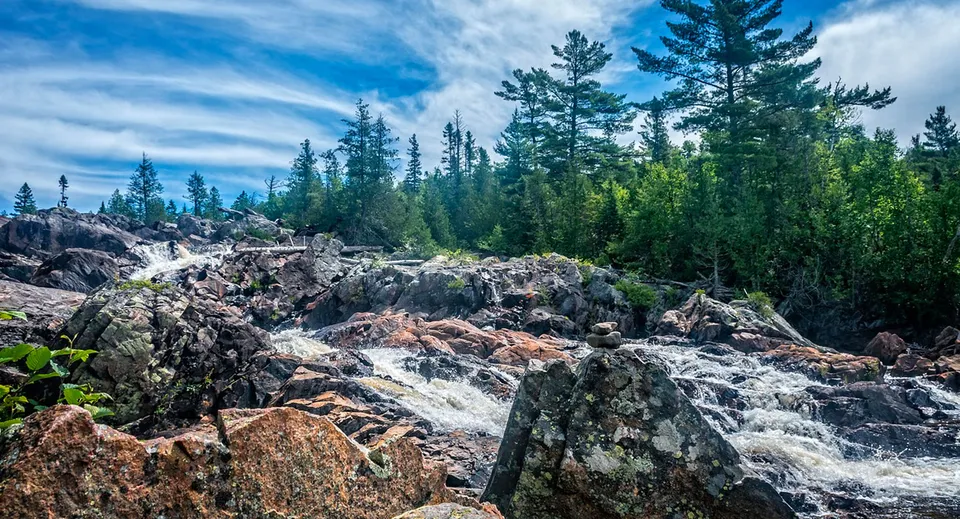 Un paesaggio roccioso con una cascata e alberi sempreverdi nel terreno del Woodbridge College.