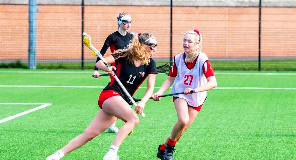 Le studentesse della Moreton Hall School giocano una partita di hockey sul campo sintetico davanti a un edificio in mattoni.