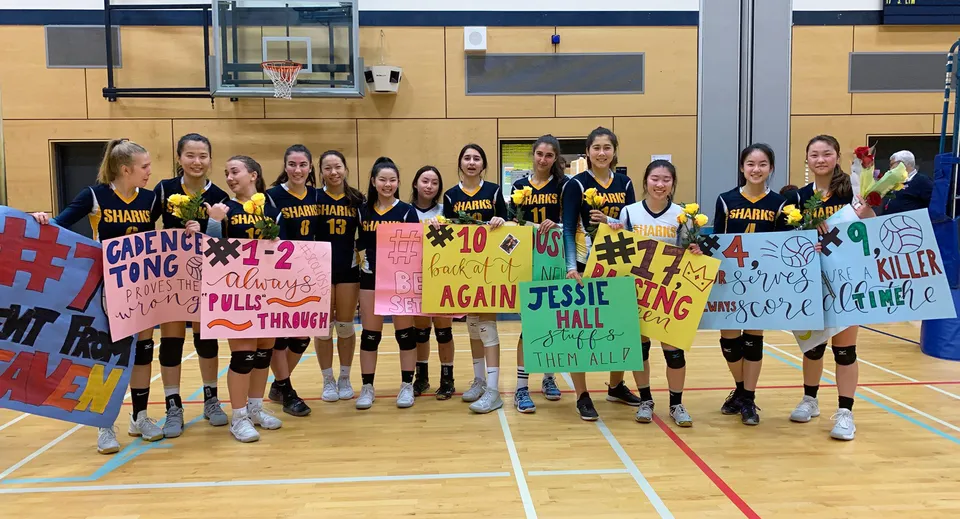 Un gruppo di giocatrici di basket della Steveston-London Secondary School con degli striscioni nella palestra.
