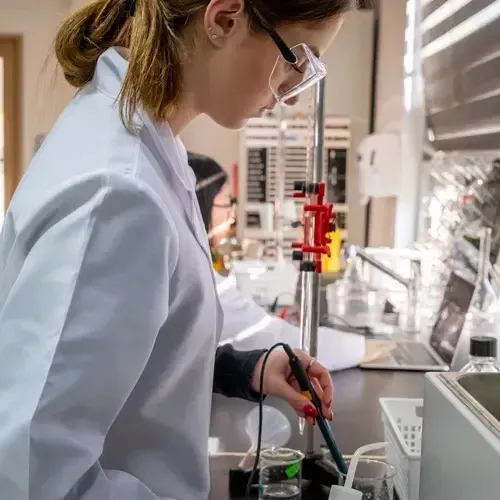 Eine Person im weißen Laborkittel steht im Labor der Taejon Christian International School vor wissenschaftlichen Geräten.