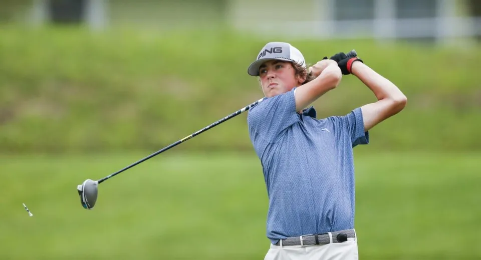 Uno studente della Sidcot School colpisce una pallina da golf su un campo d'erba.