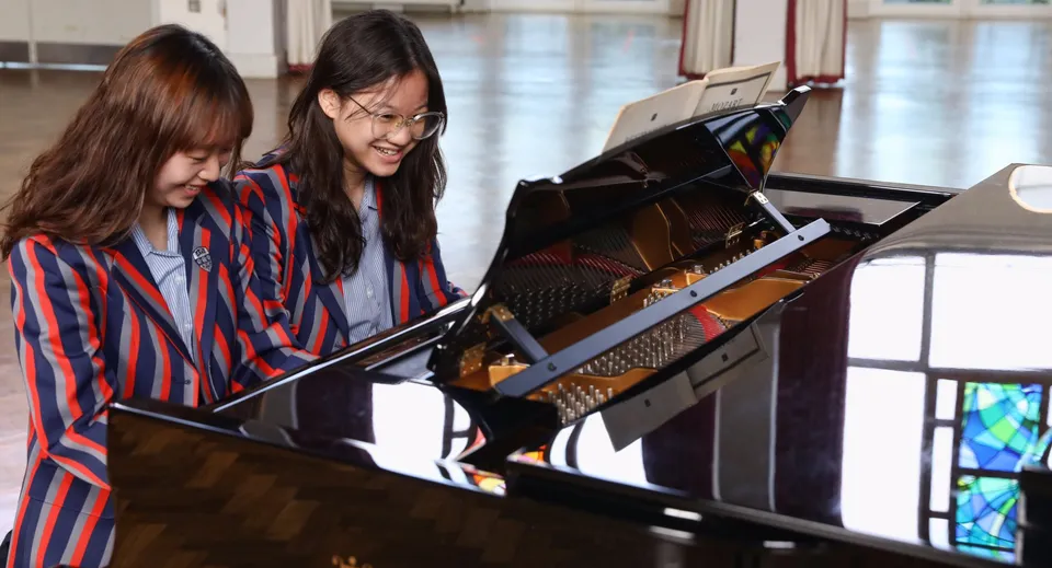 Due studentesse suonano il pianoforte insieme nel campus del Bishopstrow College.