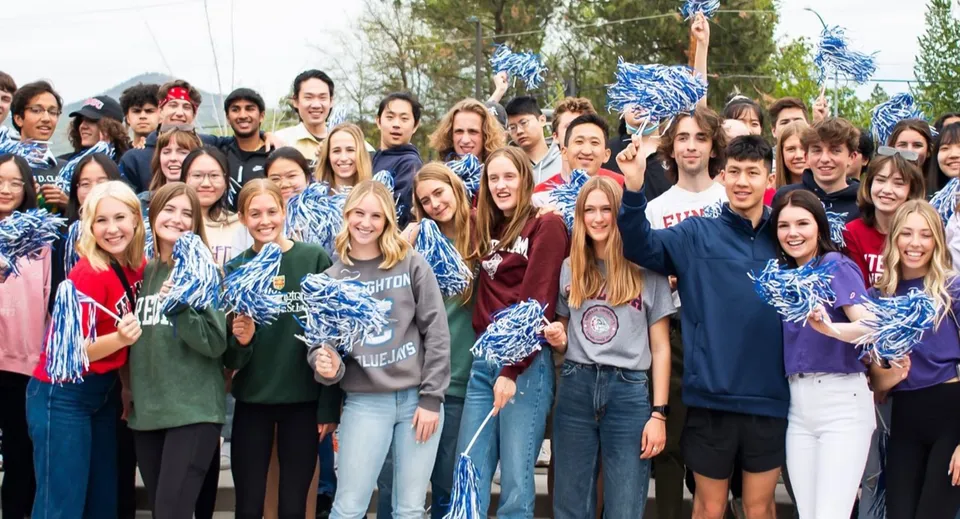 Un grande gruppo di studenti e studentesse della St. Mary's School si raduna all'aperto davanti agli alberi.