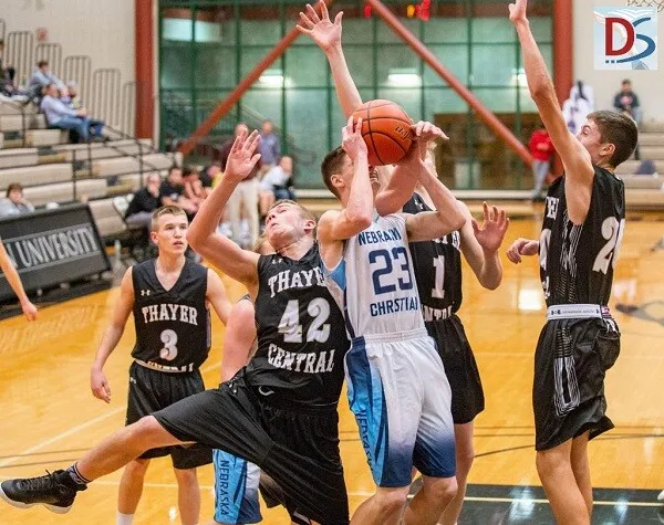 Estudiantes de Nebraska Christian Schools juegan al baloncesto en la cancha con espectadores en el fondo.