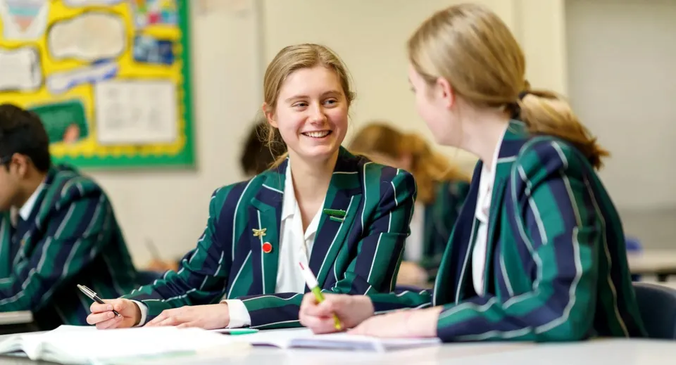Due studentesse della Lincoln Minster School conversano in un'aula vivace e colorata.