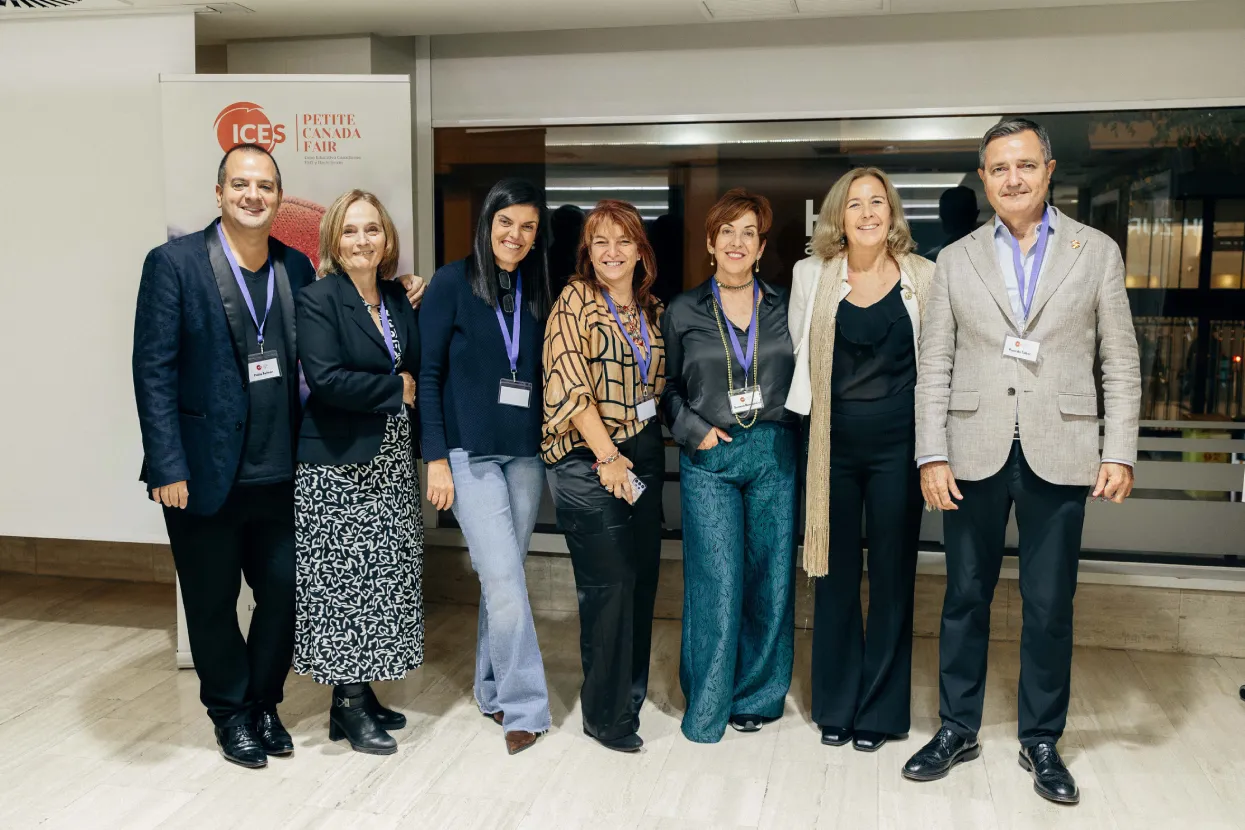 Equipo de ICES posando junto al cartel de una feria educativa sobre Canadá