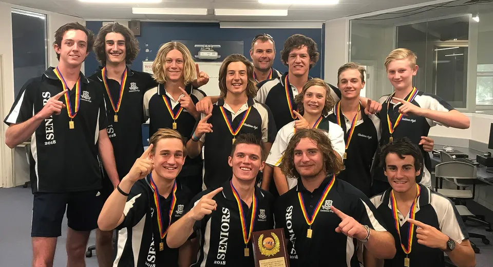 Un gruppo della Gladstone High School posa in un'aula con medaglie e un trofeo.
