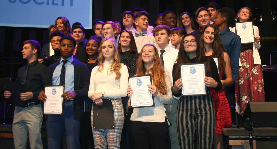 Gli studenti della Smithtown Christian School ricevono un premio sul palco davanti allo sfondo della Society.