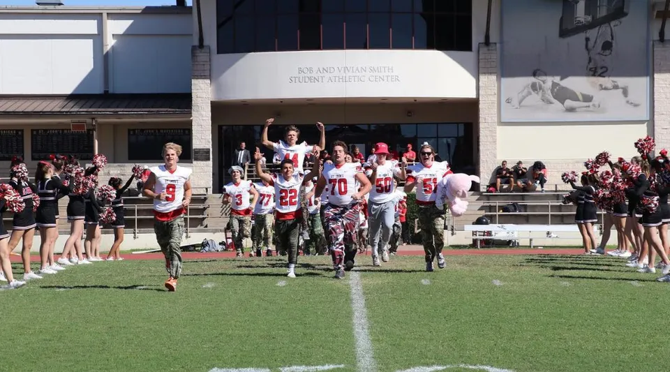 Un gruppo di studenti si trova come squadra sportiva sul campo da gioco davanti all'edificio della St. John's School.