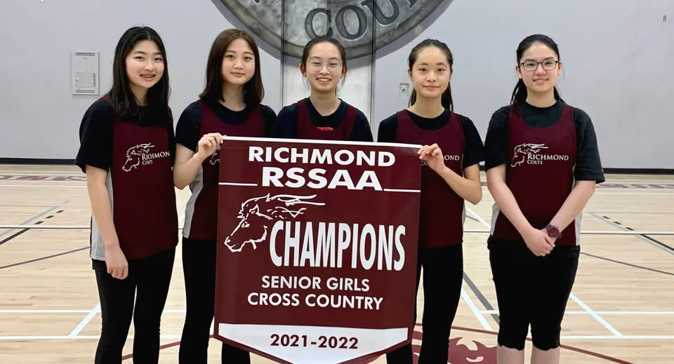 Cinque studentesse della Richmond Secondary School tengono uno striscione come RSSAA Champions nel Cross Country Senior femminile 2021-2022.