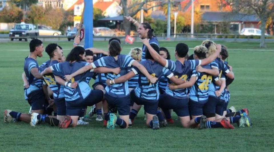 Un gruppo di studenti in uniforme blu e bianca si trova sul campo davanti all'edificio della Western Heights High School.