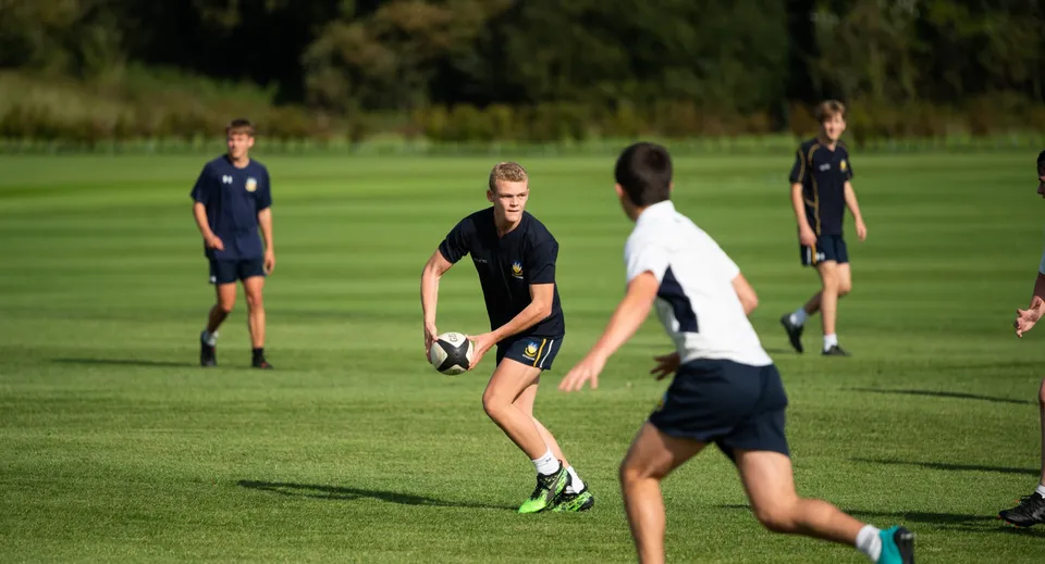 Gli studenti della Bryanston School giocano a rugby su un campo in erba.