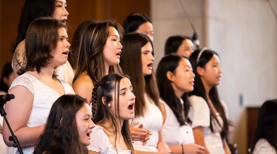 Un gruppo di giovani studentesse della Northfield Mount Hermon School canta insieme su un palco.