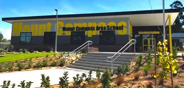 Si vede l'edificio della Mount Compass Area School con una grande insegna gialla e una scalinata che porta all'ingresso.