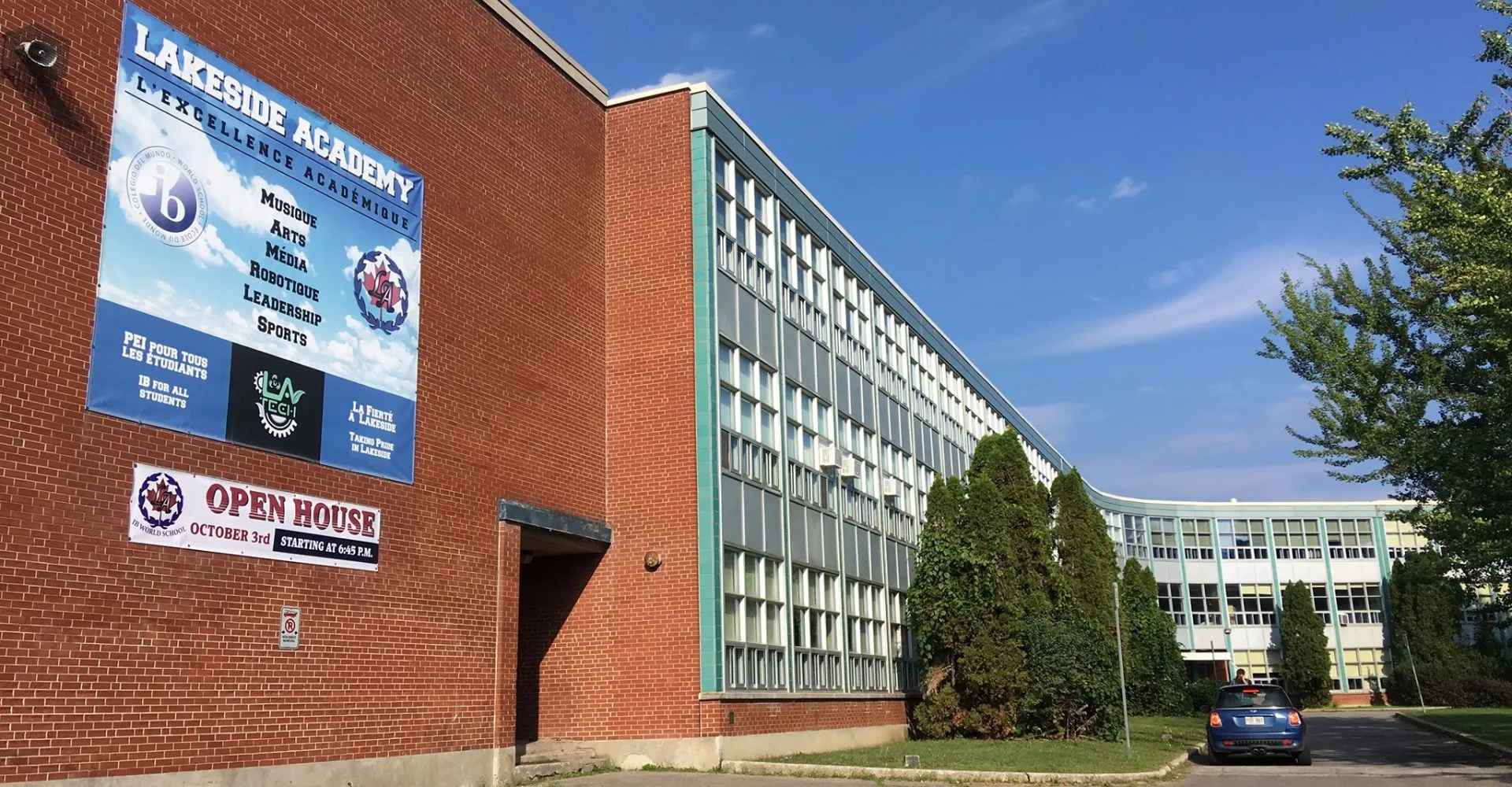 L'edificio in mattoni della Lakeside Academy è circondato da alberi sotto un cielo azzurro e limpido.