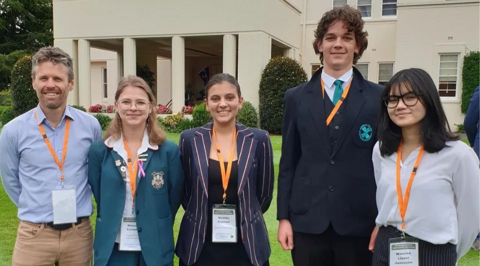 Cinque studenti si trovano davanti a un edificio con veranda e giardino nel campus del Canberra College.