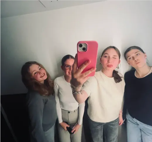 Vier Mädchen machen ein Spiegel-Selfie mit einem rosa Handy in Frankreich