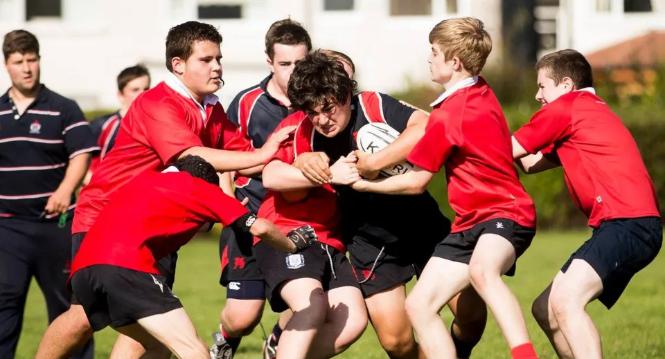 Studenti del Wesley College, con uniformi sportive rosse e nere, sono visibili in un campo sportivo mentre svolgono un'attività fisica.