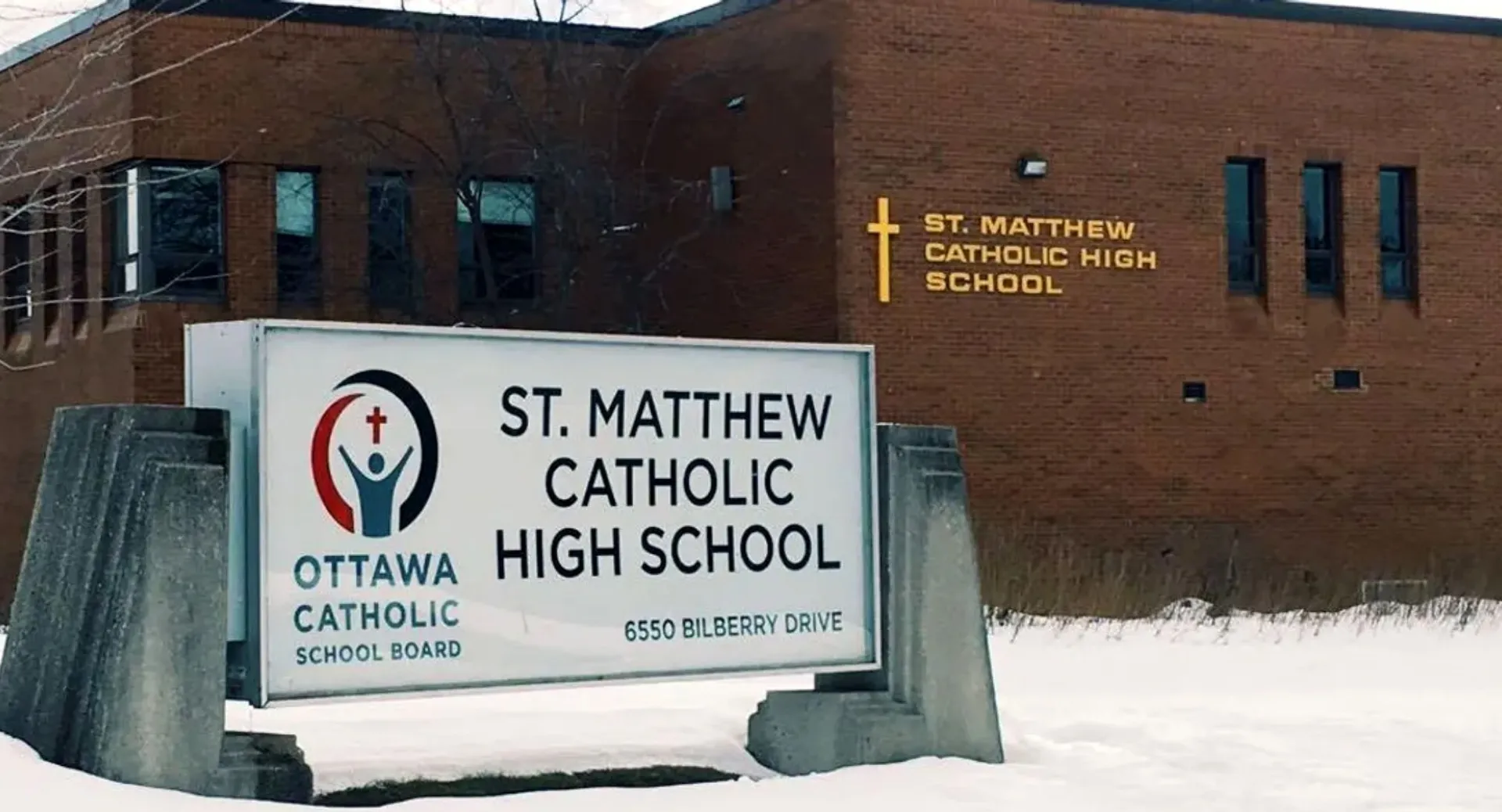 L'edificio in mattoni della St. Matthew High School con il cartello scolastico su un terreno innevato.