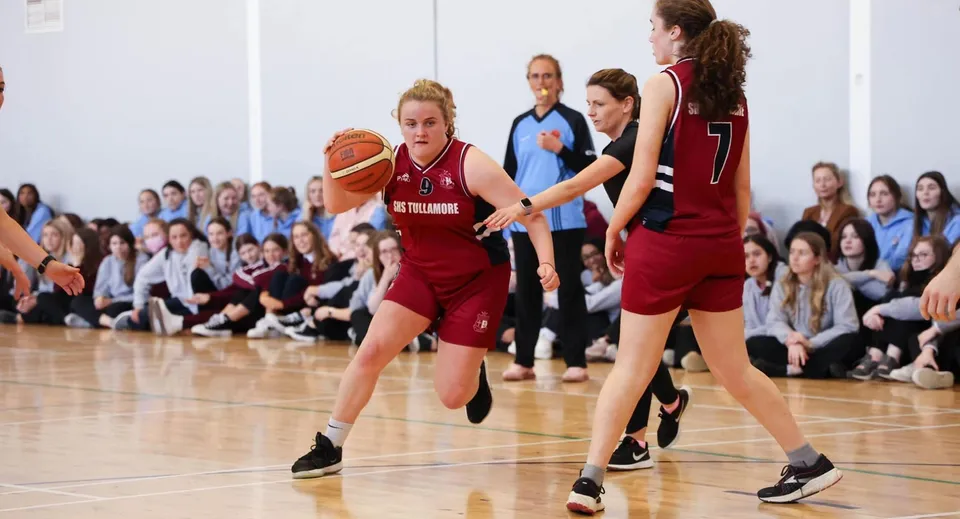 Delle studentesse giocano una partita di basket nella palestra della Sacred Heart Secondary School a Tullamore davanti al pubblico.