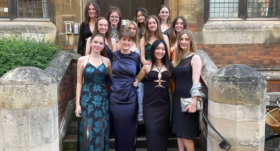 Un gruppo di giovani donne in abito formale è insieme davanti a un edificio storico in pietra nel campus della The Leys School.
