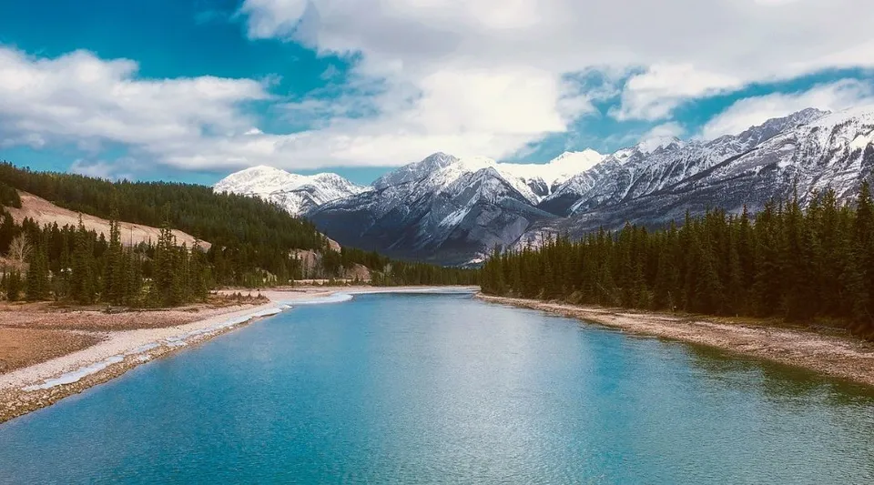 Un fiume tranquillo scorre attraverso un paesaggio montano con cime innevate vicino alla Notre Dame High School a Calgary.