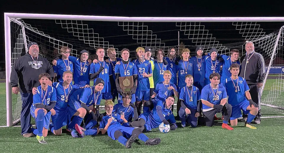 Gli studenti della Lee Academy festeggiano la loro vittoria sul campo da calcio e tengono in mano una coppa.