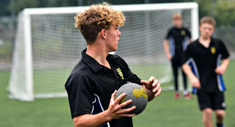 Uno studente della Leighton Park School tiene un pallone tra le mani sul campo sportivo.