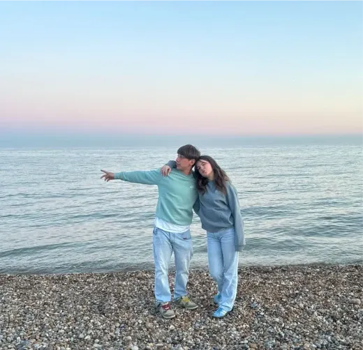 Ein Paar umarmt sich bei Sonnenuntergang an einem Kiesstrand in England