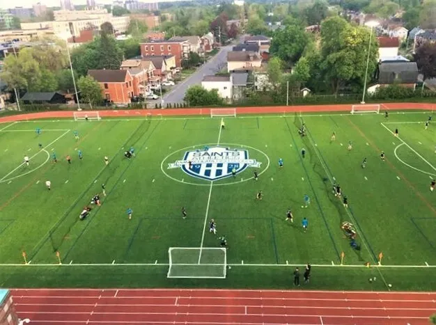 Vista aérea del campo deportivo de la Immaculata Regional School con el logotipo de la escuela en el centro.