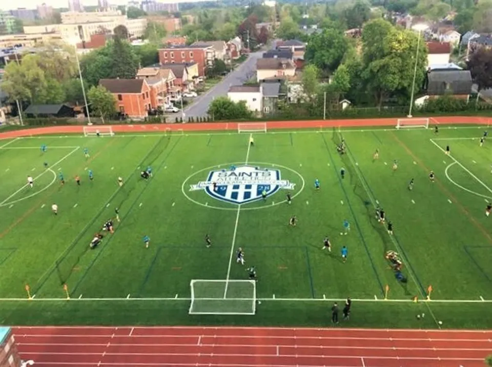 Vista aerea del campo sportivo della Immaculata Regional School con il logo della scuola al centro.