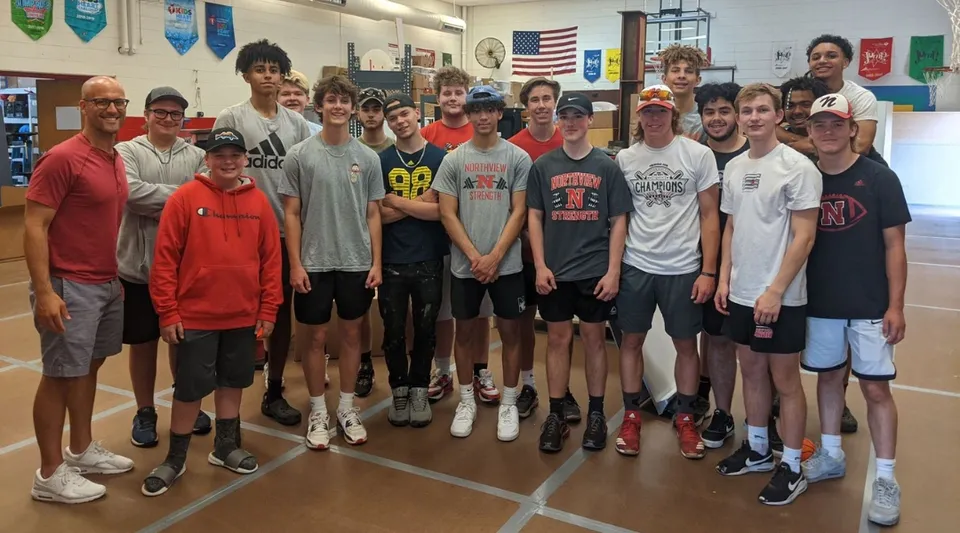 Un gruppo di studenti si trova insieme in un'aula del campus della Northview High School con bandiere sullo sfondo.