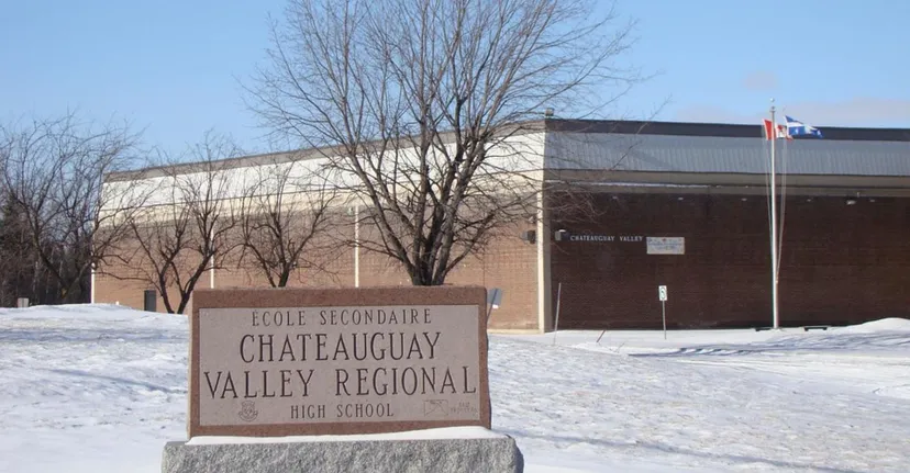 L'insegna della scuola coperta di neve si trova davanti all'edificio in mattoni della Chateauguay Valley Regional High School.