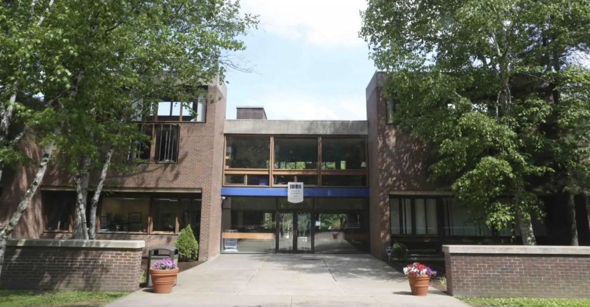 L'edificio moderno in mattoni della Allendale Columbia School con grandi finestre e ingresso coperto circondato da alberi.