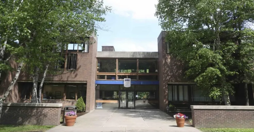 L'edificio moderno in mattoni della Allendale Columbia School con grandi finestre e ingresso coperto circondato da alberi.
