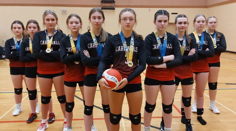 Un gruppo di pallavoliste si trova insieme nella palestra della Roncalli Central High.