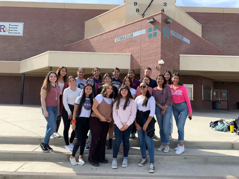 Un gruppo di studentesse è in piedi davanti a un edificio in mattoni nel campus della Ridgeview High School.