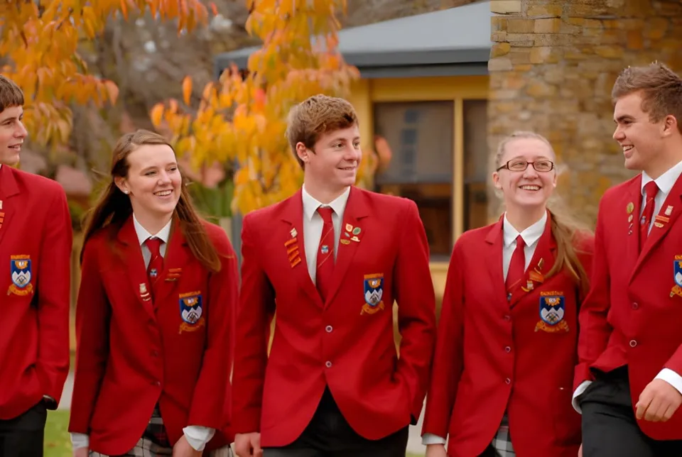 Cinque studenti della Dunstan High School in divisa scolastica rossa camminano insieme all'aperto sorridendo.
