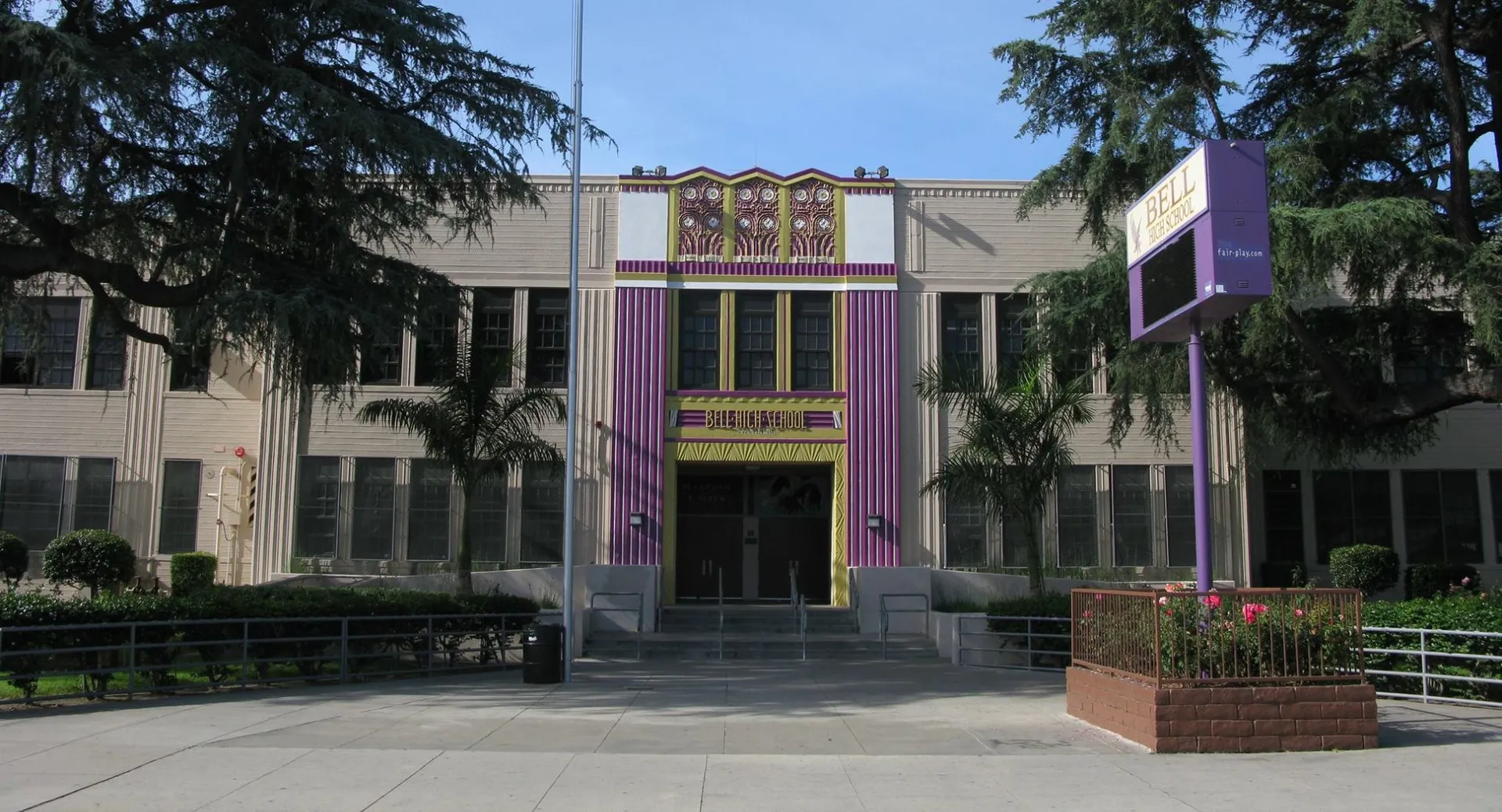 L'edificio principale della Bell High School con dettagli viola all'ingresso e un cartello nel piazzale antistante.