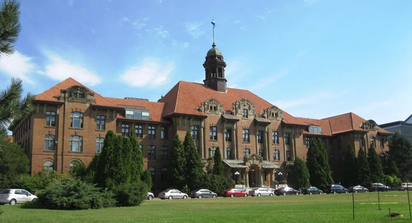 L'edificio storico in mattoni del John Abbott College con tetto rosso e torretta davanti a un prato.