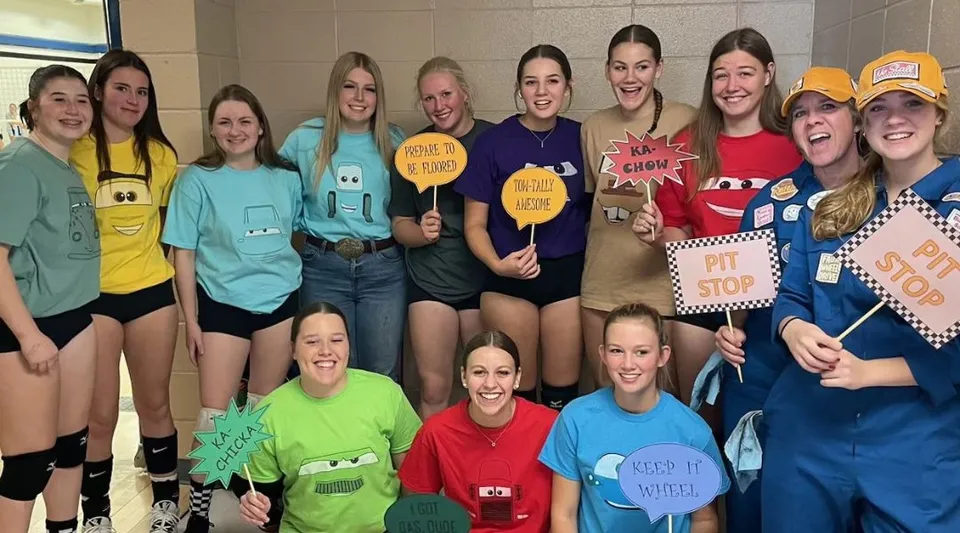 Un gruppo di studentesse della Kate Andrews High School tiene in mano cartelli colorati con messaggi divertenti e incoraggianti.