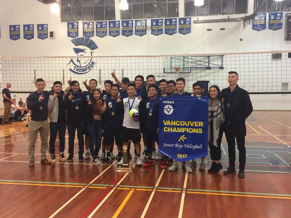 La squadra di pallavolo della David Thompson Secondary School posa nella palestra con uno striscione del campionato.