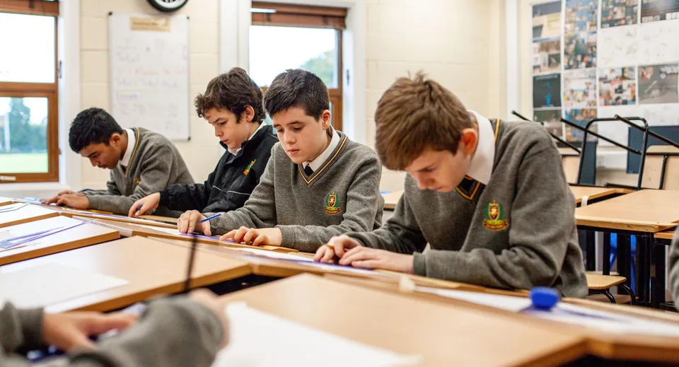 Studenti in divisa scolastica lavorano concentrati nell'aula del De la Salle College Churchtown.