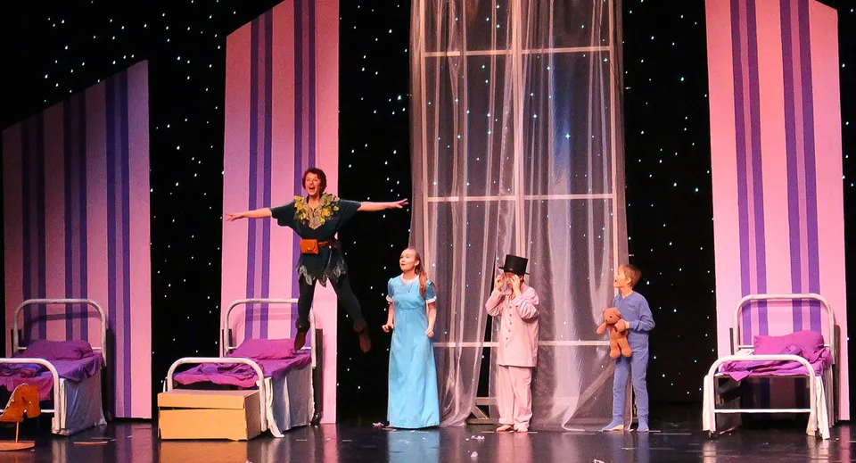 Studenti della Saint John's Prep presentano uno spettacolo teatrale con costumi colorati e uno sfondo stellato.